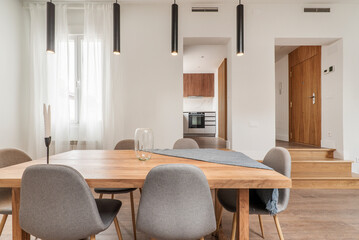 Natural wood dining table in the living room of an apartment with sloping ceilings