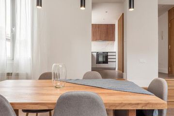 Natural wood dining table in an attic living room with wooden steps and access to an open kitchen with wooden furniture