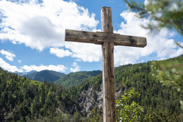 Cross on the summit of a mountain with blue cloudy sky an view on mountains and trees