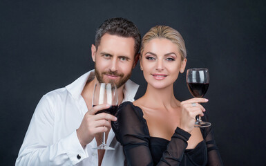 Romantic couple of man and woman celebrating holiday with red wine on black background