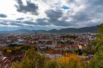 Aerial panorama view of Graz city old town Lend in west bank of Mur river with Kunsthaus and Mariahilfkirche from Schlossberg on autumn day with blue sky cloud, colorful trees, Graz, Styria, Austria