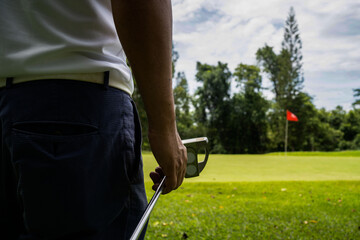 man white shirt blue pants In his hand, the putter prepares for the next golf shot.