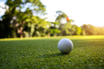 Golf ball is on a green lawn in a beautiful golf course with morning sunshine.