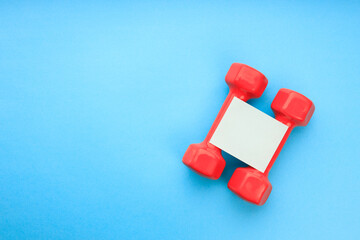 two red dumbbells and an empty square-shaped paper without an inscription