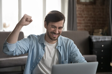 Triumphant man sit desk with laptop read great on-line news celebrate success feels happy. Business advance, get long-awaited invitation, bank loan approve, growth, gambling, lottery victory concept