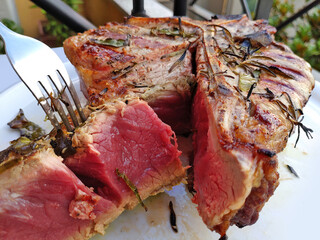 Grilled Florentine T-bone beef steak cut in a round white plate