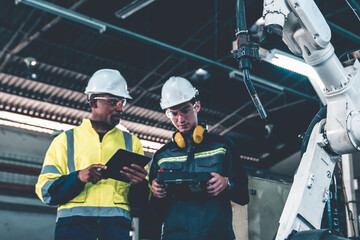 Factory workers working with adept robotic arm in a workshop . Industry robot programming software...