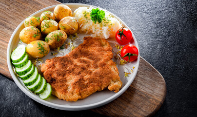 Pork cutlet coated with breadcrumbs with potatoes and cabbage