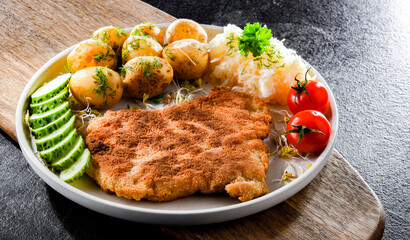 Pork cutlet coated with breadcrumbs with potatoes and cabbage