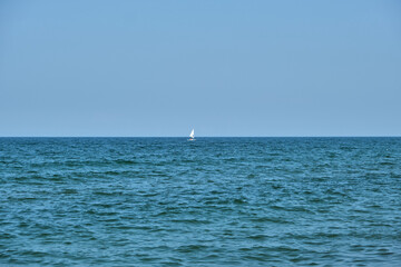 Obraz premium Small white boat sailing across a beautiful turquoise sea.