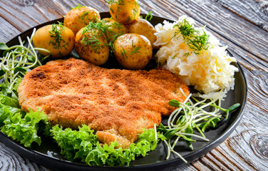 Pork cutlet coated with breadcrumbs with potatoes and cabbage - obrazy, fototapety, plakaty
