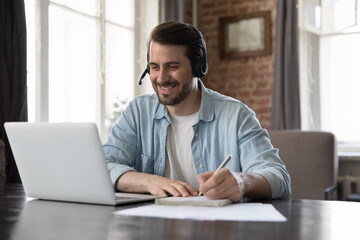 Smiling millennial man wear headset take part in educational webinar, on-line lesson, remote...