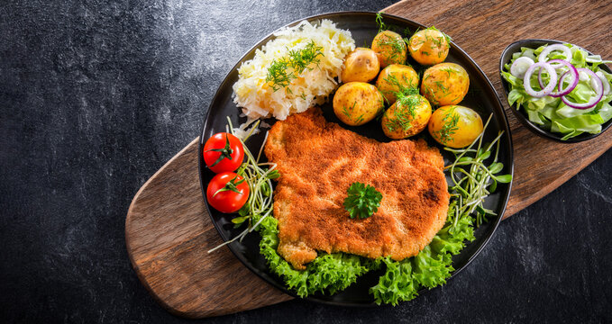 Pork cutlet coated with breadcrumbs with potatoes and cabbage