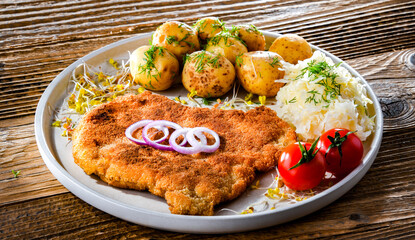 Pork cutlet coated with breadcrumbs with potatoes and cabbage