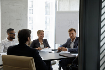 In modern office board room team of young and middle-aged diverse businesspeople take part in group...