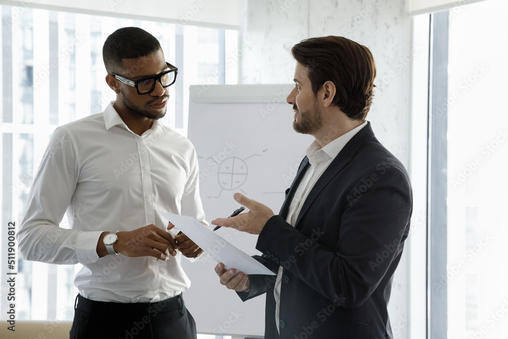 Wall mural two businessmen, african and caucasian partners standing in modern office board room negotiating, di