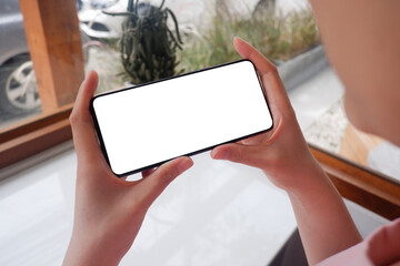 Mockup picture of business woman’s hands holding smart phone with white blank screen in modern...