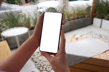 Mockup picture of business woman’s hands holding smart phone with white blank screen in modern place