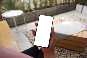 Mockup picture of business woman’s hands holding smart phone with white blank screen in modern place