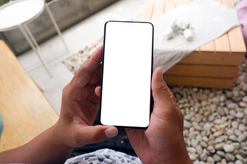 Mockup picture of business woman’s hands holding smart phone with white blank screen in modern place