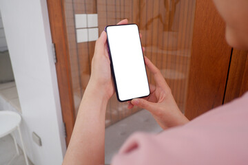Mockup picture of business woman’s hands holding smart phone with white blank screen in modern place