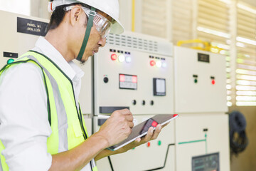Electrical engineer holding tablet computer tools to inspecting the electrical system in a factory,...