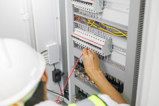 Electrical engineer or repairman holding a multimeter digital to inspecting the electrical system in a factory.