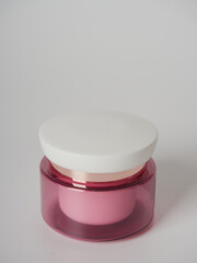 Pink lip balm in jar on a white background