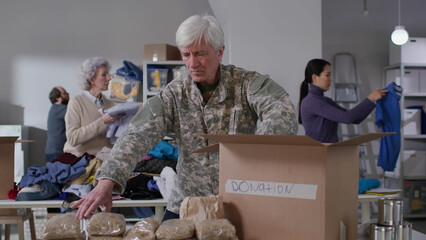 Military officer pack food in boxes for donation in volunteering center