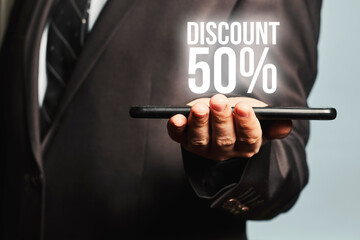 Concept of discounts on the Internet. The hand with the tablet shows the hologram 50 percent discount