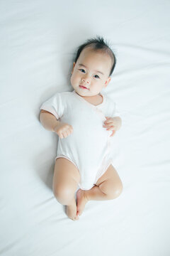 Cute little asian baby on bed with soft blanket indoors