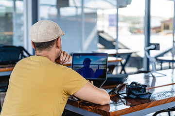Image of the back of a digital nomad man working online with his laptop. 