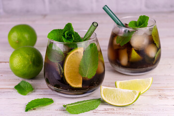 Two cuba libre cocktails of cola, lime and mint.

