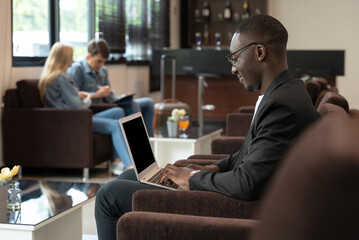 African businessman working on laptop while waiting for his flight at airport lounge - 511910607