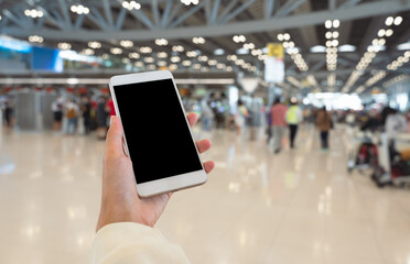 Woman hand using smart phone with blurred airport terminal background.