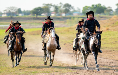 Group of cowboy and cowgirl ride horse on road with high speed near water reservoir with day light.