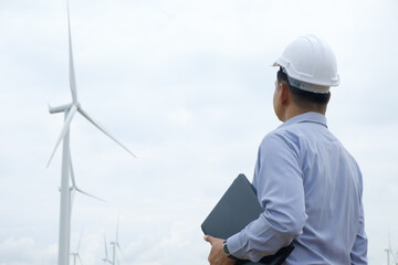 Engineers windmills are working on laptop with the wind turbine in background..Concept of...