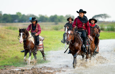 Group of cowboy and cowgirl ride horse through water in reservoir with day light.