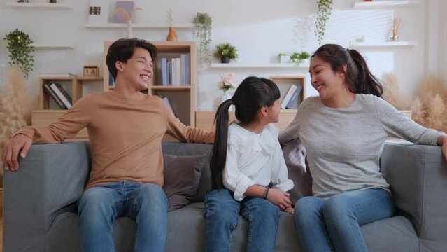 Happy family mum dad with cute little kids daughter having fun relax on sofa together, Young parents rest on sofa hug children spend weekend at home laugh have fun to talking together.