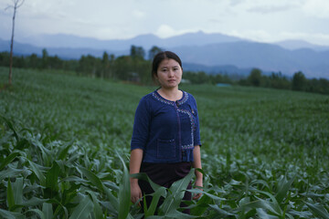 A local woman stands in a cornfield in the dark rainy season.