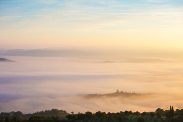 Picturesque view of countryside  of Tuscany in the light of the rising sun in foggy morning, Italy