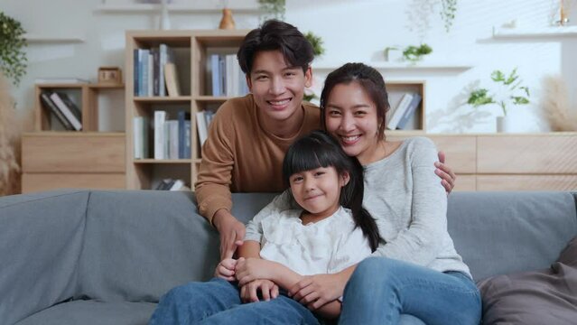 Happy family mum dad with cute little kids daughter having fun relax on sofa together, Young parents rest on sofa hug children spend weekend at home laugh have fun to talking together.