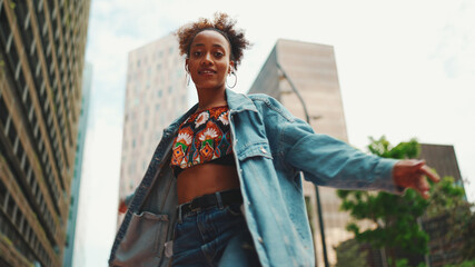 Closeup, smiling African girl with ponytail wearing denim jacket, in crop top with national pattern...