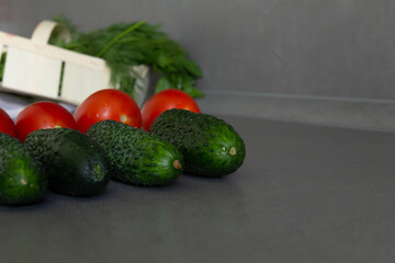 Fresh tomatoes, green cucumbers and fragrant greens salad in a bamboo basket laid out exactly in a row on the kitchen table. The cook is a perfectionist. Cook according to the recipe