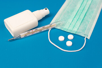 medical protective face mask, thermometer, pills and hand sanitizer
