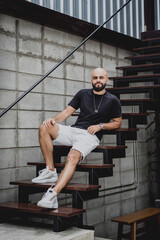 Naklejka premium A young man in t-shirt and shorts on the stairs at city streets