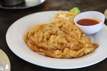Delicious omelet on plate with tomato sauce