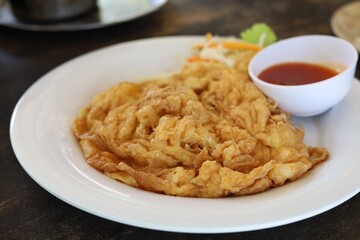 Delicious omelet on plate with tomato sauce