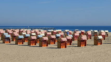 Naklejka premium Sandstrand an der Ostsee bei Travemünde mit vielen Strandkörben entlang dem Meer unter blauem Himmel