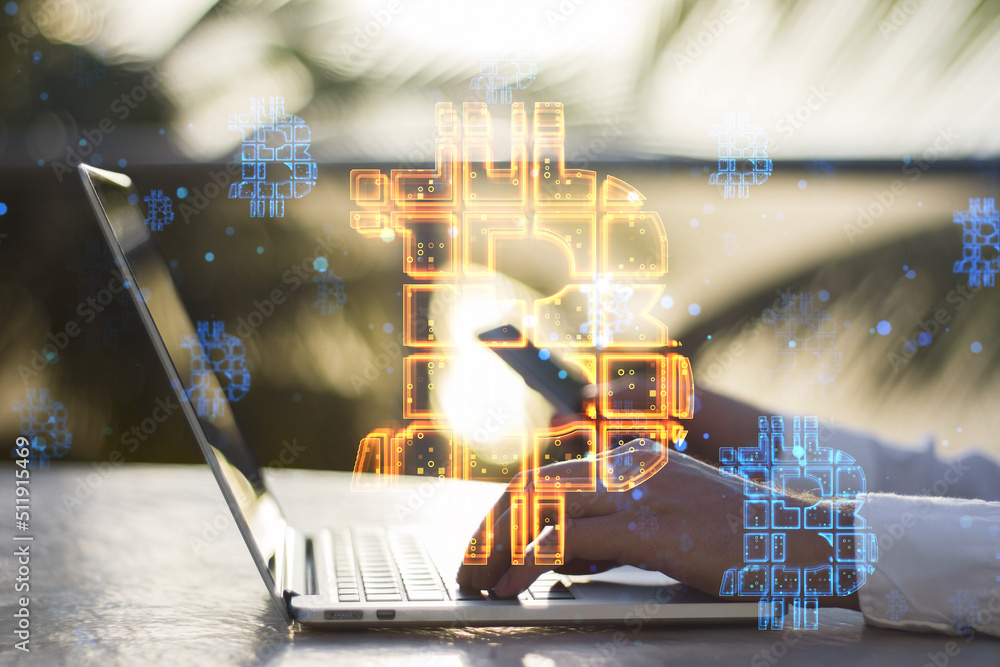 Poster hands using laptop and cellphone with abstract glowing bitcoin sign hologram on desktop and blurry o